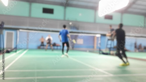 Blurred environment view of a badminton gym while people play and learn the indoor game.