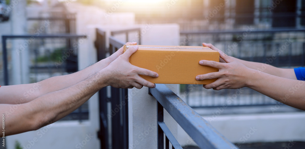 Obraz premium Asian delivery express courier young man use giving boxes to woman customer he wearing protective face mask at front home