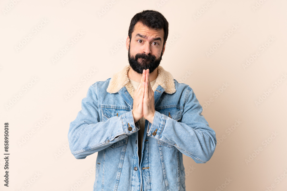 Caucasian man with beard over isolated background keeps palm together. Person asks for something Caucasian man with beard over isolated background keeps palm together. Person asks for something