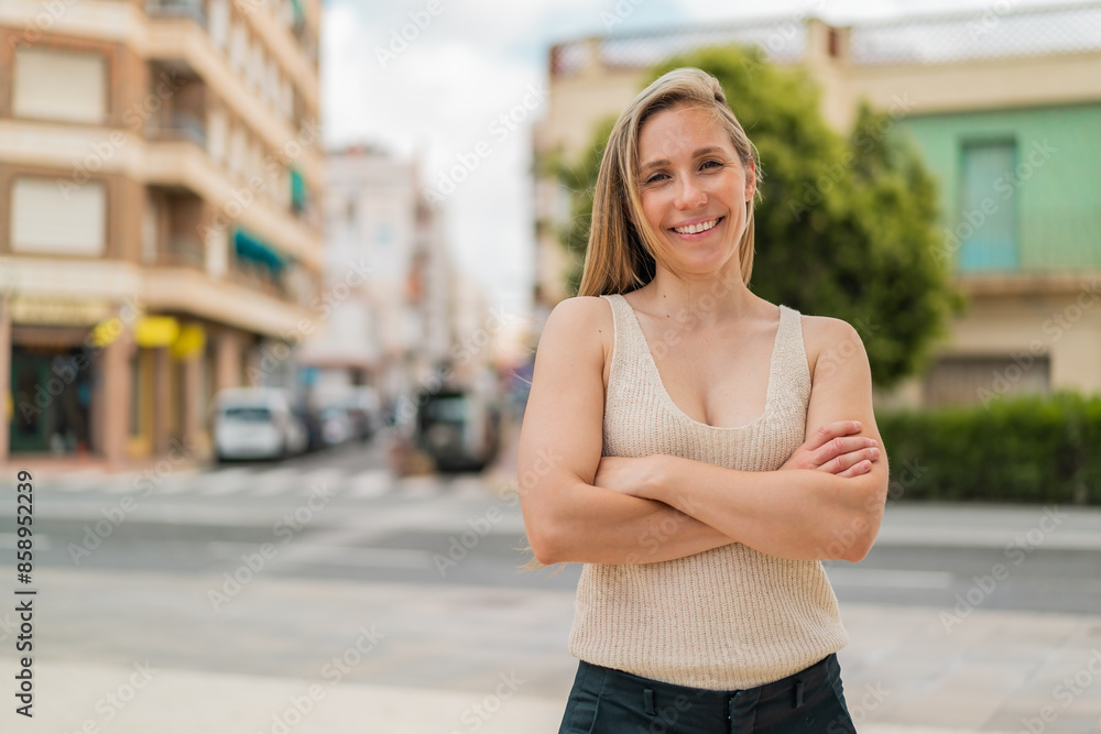 Young blonde woman at outdoors keeping the arms crossed in frontal position Young blonde woman at outdoors keeping the arms crossed in frontal position