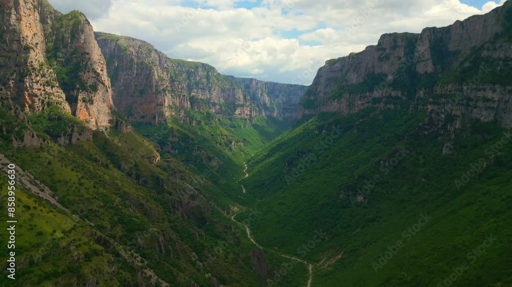 A stunning aerial photograph showcasing the dramatic depth of Vikos Gorge in Greece, with the winding Voidomatis river snaking its way through the lush, green valley. A stunning aerial photograph showcasing the dramatic depth of Vikos Gorge in Greece, with the winding Voidomatis river snaking its way through the lush, green valley.