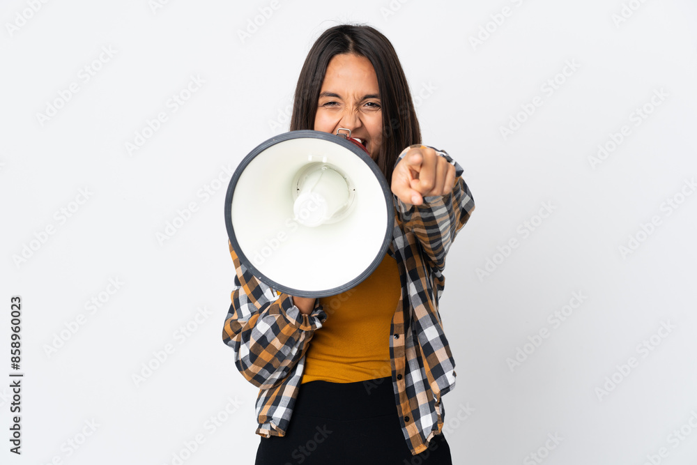 Young latin woman isolated on white background shouting through a megaphone to announce something while pointing to the front Young latin woman isolated on white background shouting through a megaphone to announce something while pointing to the front
