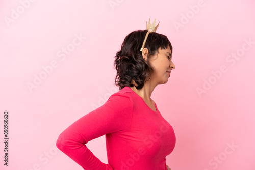 Young mixed race princess with crown isolated on pink background suffering from backache for having made an effort