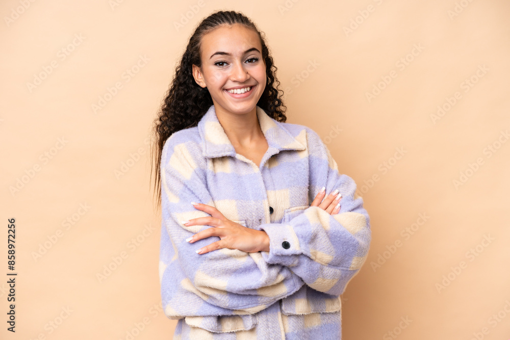 Young woman isolated on beige background with arms crossed and looking forward Young woman isolated on beige background with arms crossed and looking forward