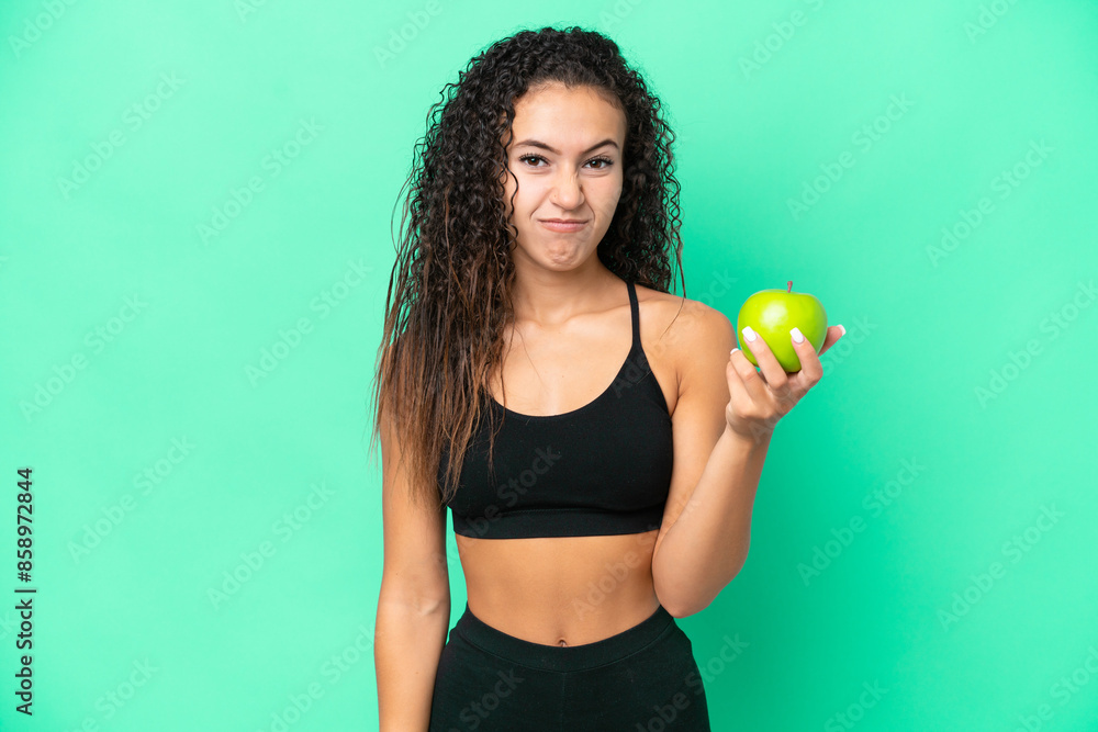 Young Arab woman with an apple isolated on green background with sad expression Young Arab woman with an apple isolated on green background with sad expression