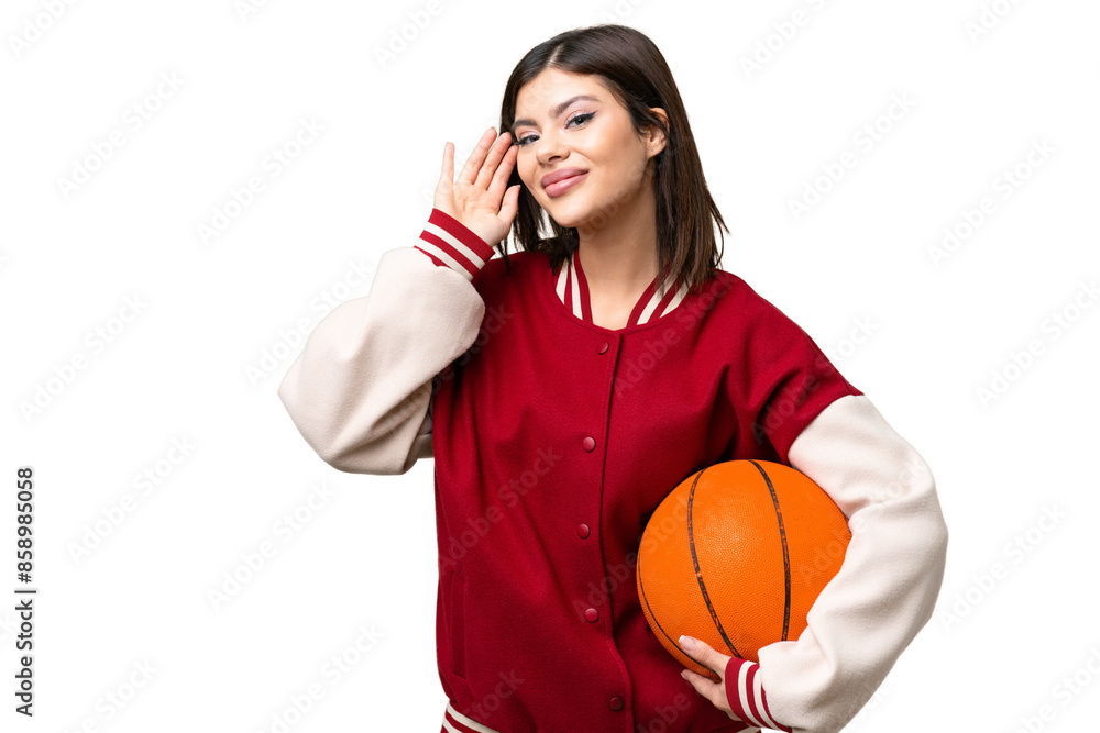 Young Russian woman playing basketball over isolated chroma key background listening to something by putting hand on the ear Young Russian woman playing basketball over isolated chroma key background listening to something by putting hand on the ear