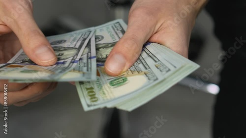 In the image, an individual is seen meticulously arranging stacks of hundreddollar bills, likely for sorting or counting, highlighting a concentration on financial tasks and operations photo