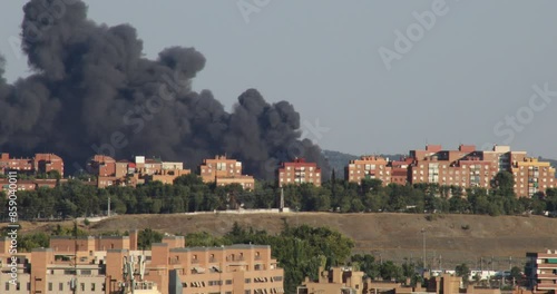 Large plume of dark, dense smoke from a fire behind buildings in the cityof Madrid, Spain
