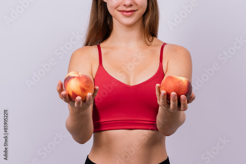 Happy cheerful young blond woman holding nectarines in hands over chest