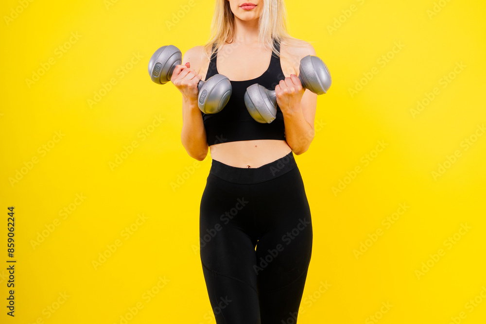 Sporty woman does the exercises with dumbbells on dark, yellow, red background. Sporty woman does the exercises with dumbbells on dark, yellow, red background.