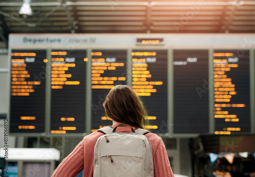 Woman, back and airport with flight schedule on board with information display for global immigration. Person, backpack and international travel with digital time table on screen, location or arrival