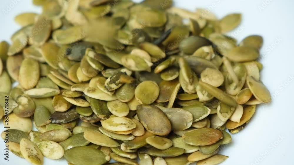 Pumpkin seed kernels pouring into the plate slow motion. Pumpkin seed kernels pouring into the plate slow motion.