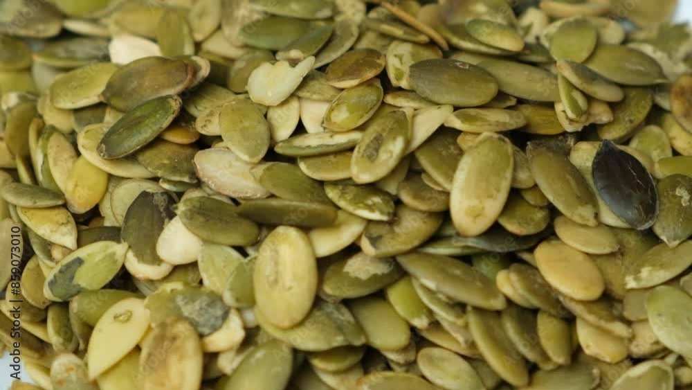 Pumpkin seed kernels pouring into the plate slow motion. Pumpkin seed kernels pouring into the plate slow motion.