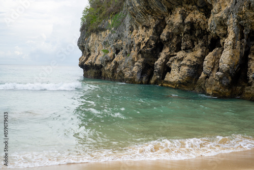 Ocean waves next to rocky cliff. Beautiful beach landscape in Tebing Beach in Aceh Besar, Indonesia. photo