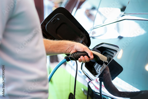 Man charging his electric car. EV charger in male hand closeup. photo