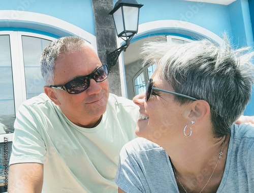 Portrait of a young adult couple in close-up, looking at each other smiling with a loving look,outdoors on a sunny day.Couple of tourists in love at the Marina Sur pier in Las Galletas,taking a selfie photo