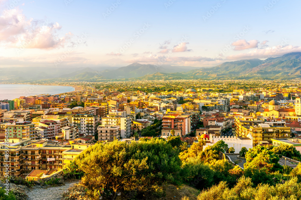 Fototapeta premium panoramic summer travel view from a hill to beautiful sea coast historical town with port, amazing ocean bay and gulf and beautiful mountains with scenic sunset on background.
