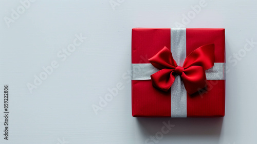A stylish red gift box with a silver ribbon and red bow, displayed on a white background for a minimalist look, real photo, stock photography