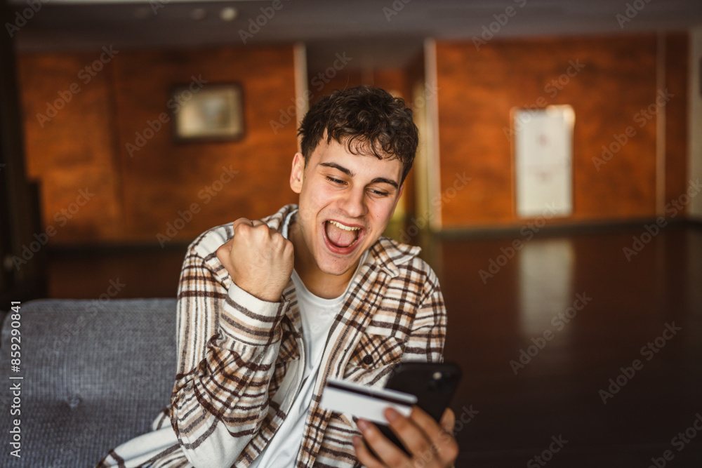 Young boy stand and buy online on mobile phone with credit card Young boy stand and buy online on mobile phone with credit card