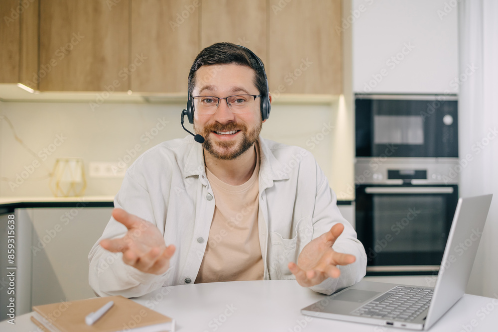 Smiling caucasian man in glasses and headset work with laptop talk to camera, student in headphones using computer Smiling caucasian man in glasses and headset work with laptop talk to camera, student in headphones using computer