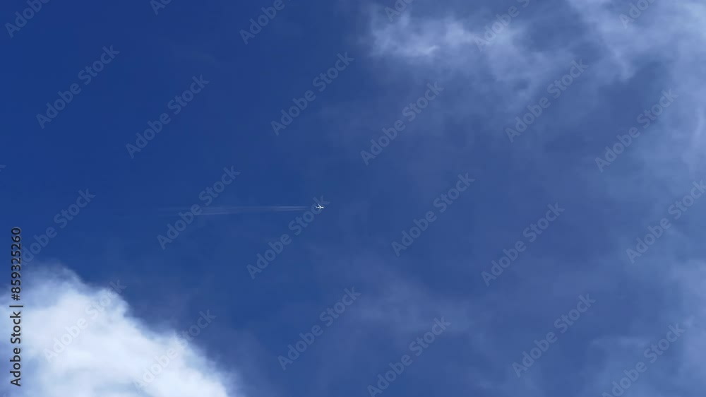 An airplane with jet contrail crossing the blue sky through the white clouds. Cloudscape. An airplane with jet contrail crossing the blue sky through the white clouds. Cloudscape.