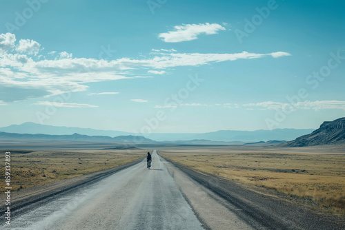 lone cyclist on a deserted road with a vast open landscape © Damian