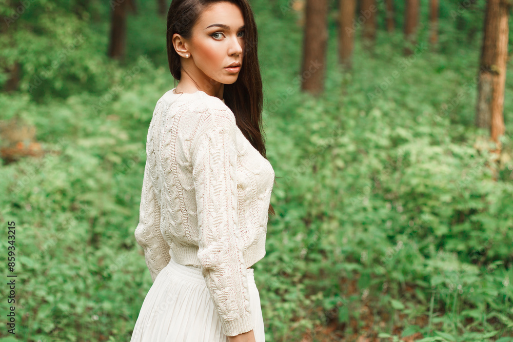 Beautiful natural fresh young woman in a fashion knitted sweater on a green natural background in the forest Beautiful natural fresh young woman in a fashion knitted sweater on a green natural background in the forest