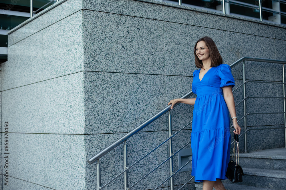 Beautiful businesswoman going down the stairs of a modern city building Beautiful businesswoman going down the stairs of a modern city building