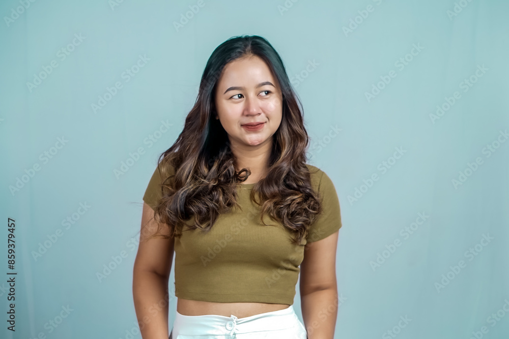 Portrait of a confident Asian woman smiling, standing looking at the camera isolated on a blue background Portrait of a confident Asian woman smiling, standing looking at the camera isolated on a blue background