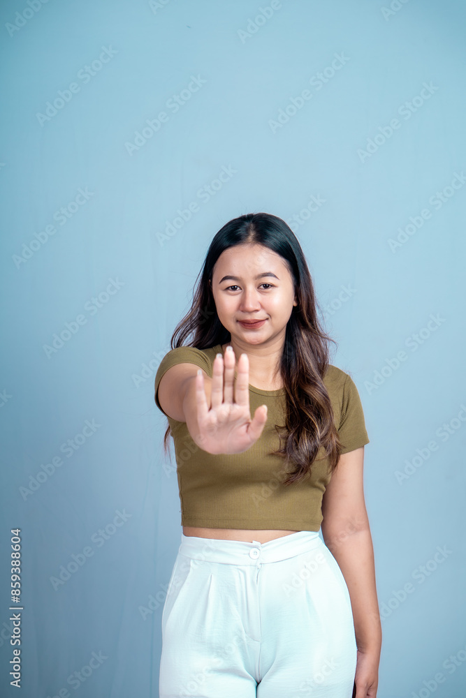 Young Asian woman wearing casual t-shirt over blue isolated background doing stop sign with palm of the hand. Young Asian woman wearing casual t-shirt over blue isolated background doing stop sign with palm of the hand.