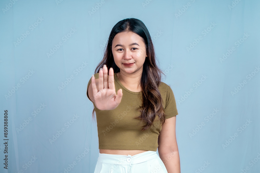 Young Asian woman wearing casual t-shirt over blue isolated background doing stop sign with palm of the hand. Young Asian woman wearing casual t-shirt over blue isolated background doing stop sign with palm of the hand.