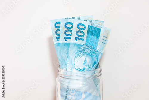 Notas de 100 Reais dentro de um cofrinho de pote de vidro. Dinheiro, Real, Brasil. Finanças, investimentos e economia brasileira. Poupança, renda fixa ou renda variável. photo
