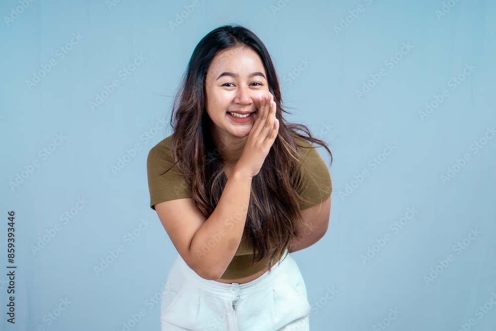 Surprised Asian woman reclines on her hands and shouting while looking at the camera over blue background Surprised Asian woman reclines on her hands and shouting while looking at the camera over blue background