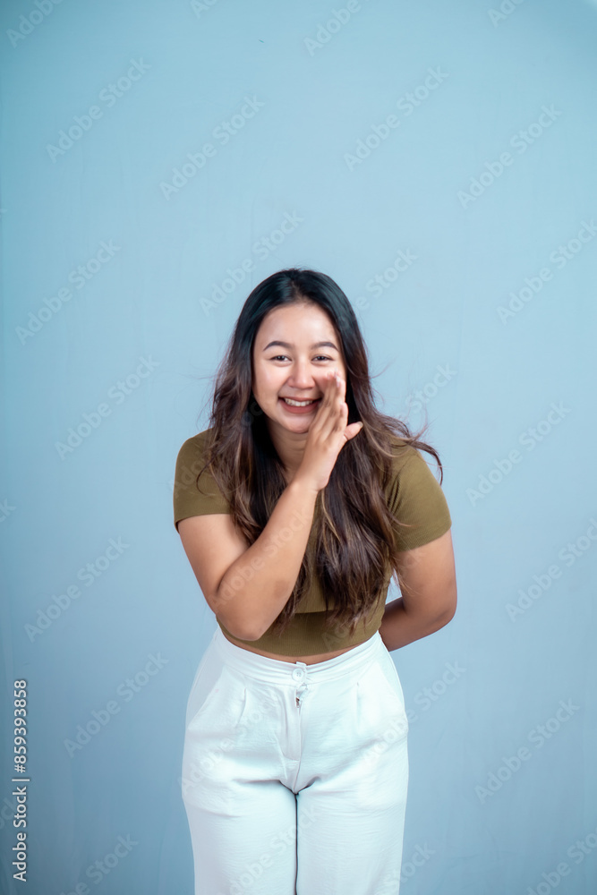 Surprised Asian woman reclines on her hands and shouting while looking at the camera over blue background Surprised Asian woman reclines on her hands and shouting while looking at the camera over blue background