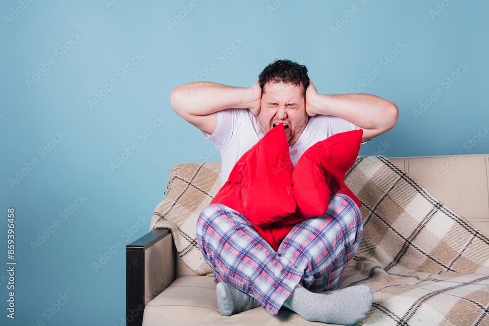 Funny fat man posing on the sofa at home. Blue background. Funny fat man posing on the sofa at home. Blue background.