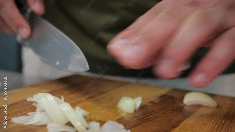 chef quickly slices the onion with a sharp knife. close-up of a man's hands and a wooden chopping board, leek chef quickly slices the onion with a sharp knife. close-up of a man's hands and a wooden chopping board, leek