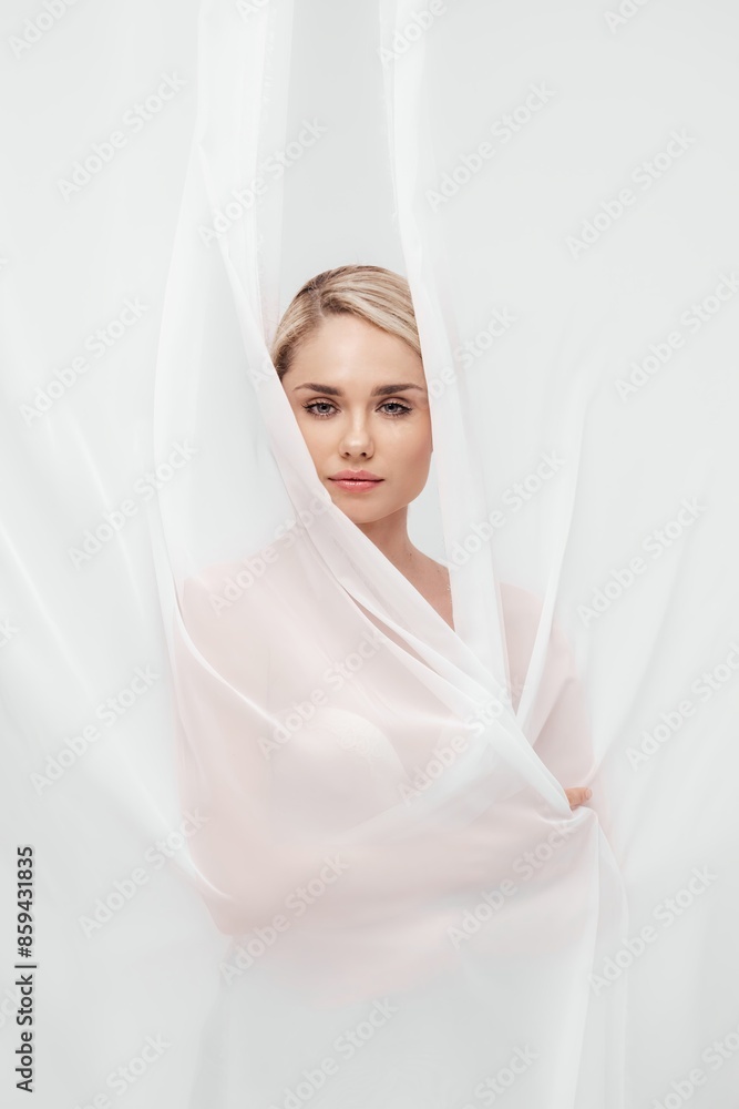 Beautiful smiling blonde female with glow skin, bare shoulders relaxing, posing at white studio background, surrounded by white veil. Beauty portrait and skincare concept. Copy space, banner. Beautiful smiling blonde female with glow skin, bare shoulders relaxing, posing at white studio background, surrounded by white veil. Beauty portrait and skincare concept. Copy space, banner.