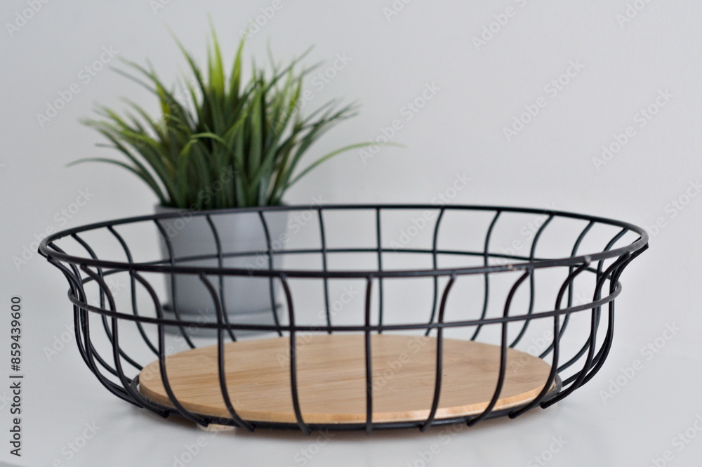Obraz premium Metal fruit basket with wooden insert with green plant on white background
