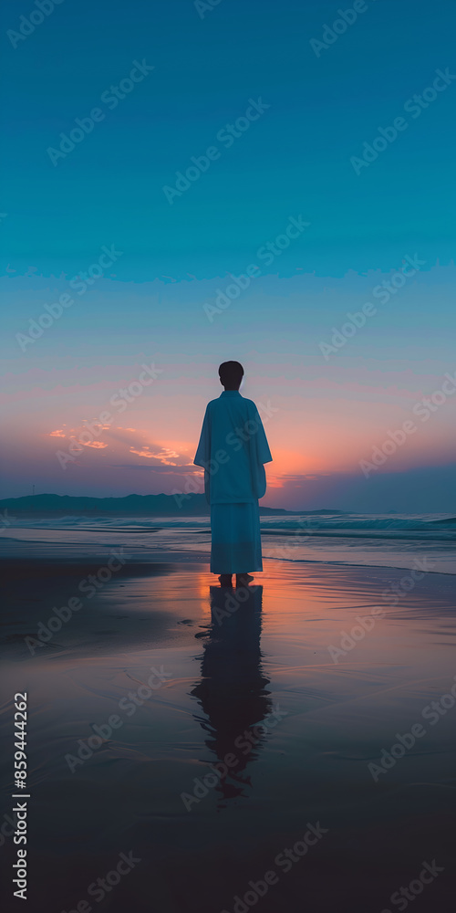 Fototapeta premium a man stands on a beach with the sun setting behind him.