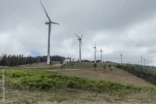 Wide angle shot of windmill farm with road populating the foreground along the mountains. Renewable energy