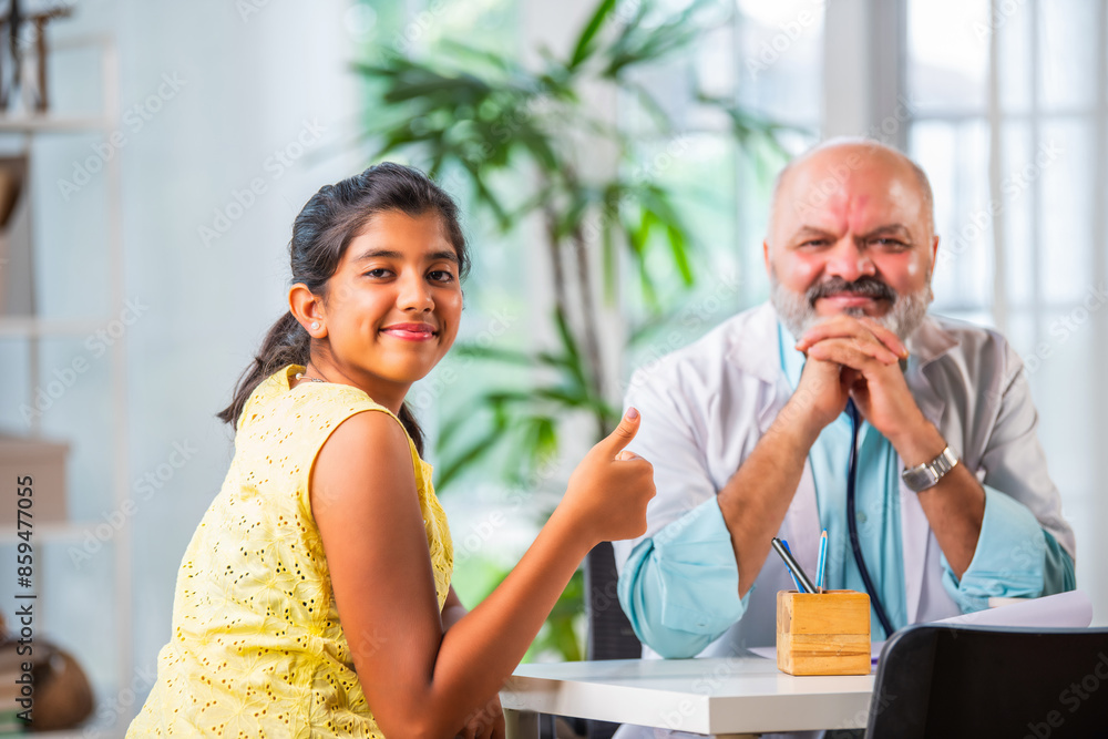 Indian asian small little girl visits Male doctor in clinic who is senior, elderly, old or matured Indian asian small little girl visits Male doctor in clinic who is senior, elderly, old or matured