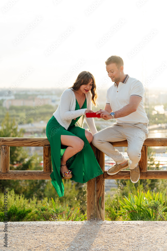 Couple sitting in the park looking at a mobile phone Couple sitting in the park looking at a mobile phone