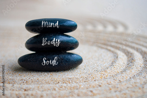 Mind, body and soul text on Zen stones with sand background
