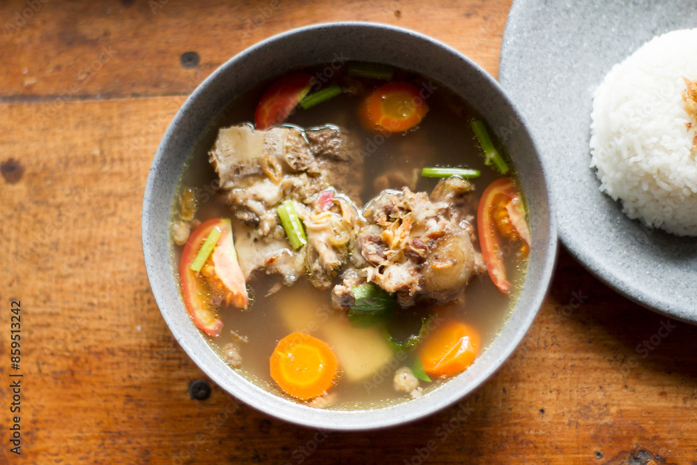 Sop Buntut or oxtail soup on a wooden table. traditional Indonesian culinary delights Sop Buntut or oxtail soup on a wooden table. traditional Indonesian culinary delights