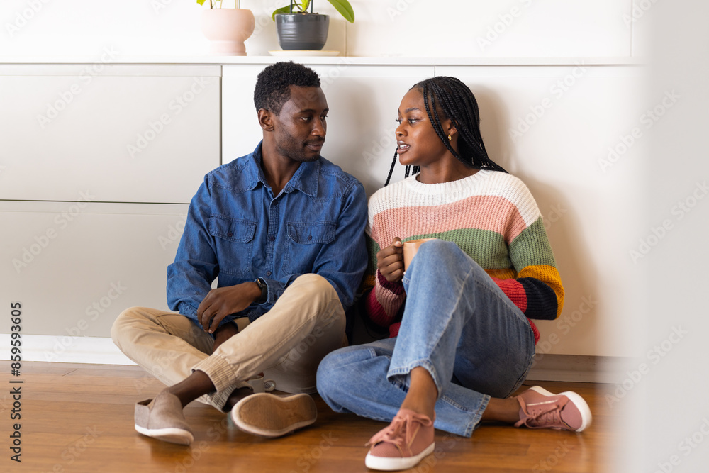 Young couple sitting on floor, talking and enjoying coffee at home Young couple sitting on floor, talking and enjoying coffee at home