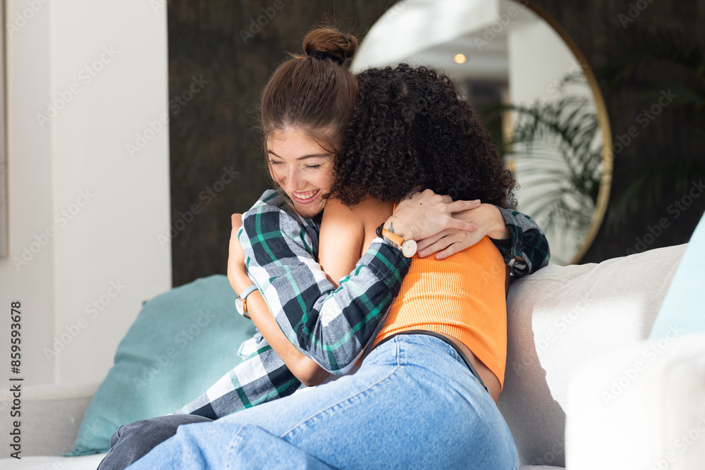 Lesbian couple embracing on couch, sharing warm hug at home Lesbian couple embracing on couch, sharing warm hug at home