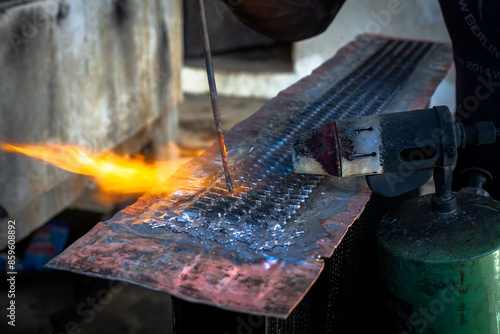Man is working at metal factory, he is welding a piece of rail using special tools. photo