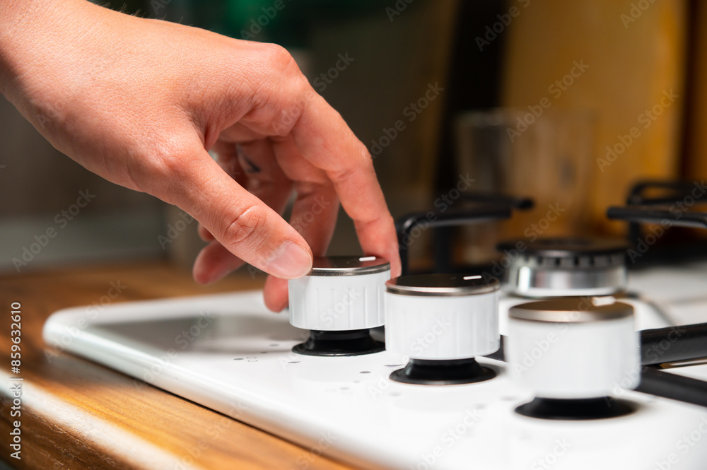 woman's hand turns on the gas stove. protection from children. Gas systems concept. Gas stove with electric ignition woman's hand turns on the gas stove. protection from children. Gas systems concept. Gas stove with electric ignition