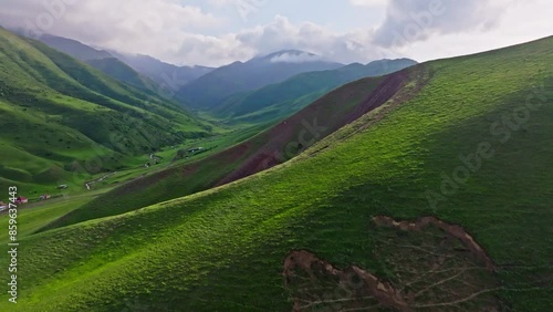 Wide open spaces with lush green hills and serene valleys under a cloudy sky, revealing natures tranquility and beauty of jailoo pastures in Kyrgyzstan photo