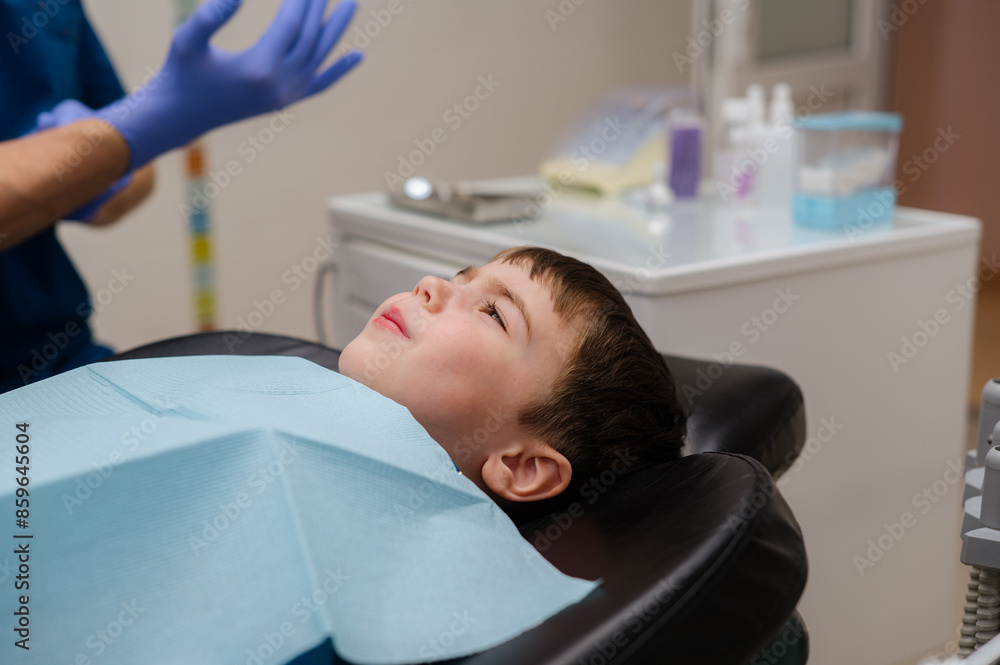 The dentist checks teeth of boy who is sitting in a dental chair. Dental treatment. The dentist checks teeth of boy who is sitting in a dental chair. Dental treatment.